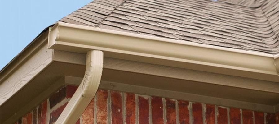 A close up of a gutter on the side of a brick house.