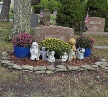 A grave in a cemetery surrounded by flowers and statues.