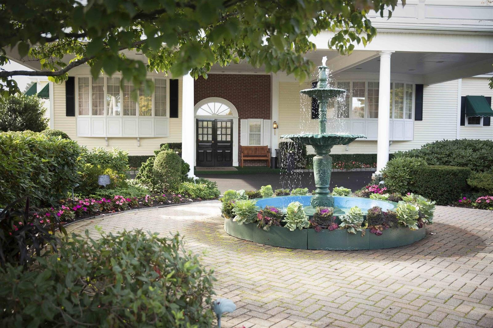 A fountain with flowers in front of a white house
