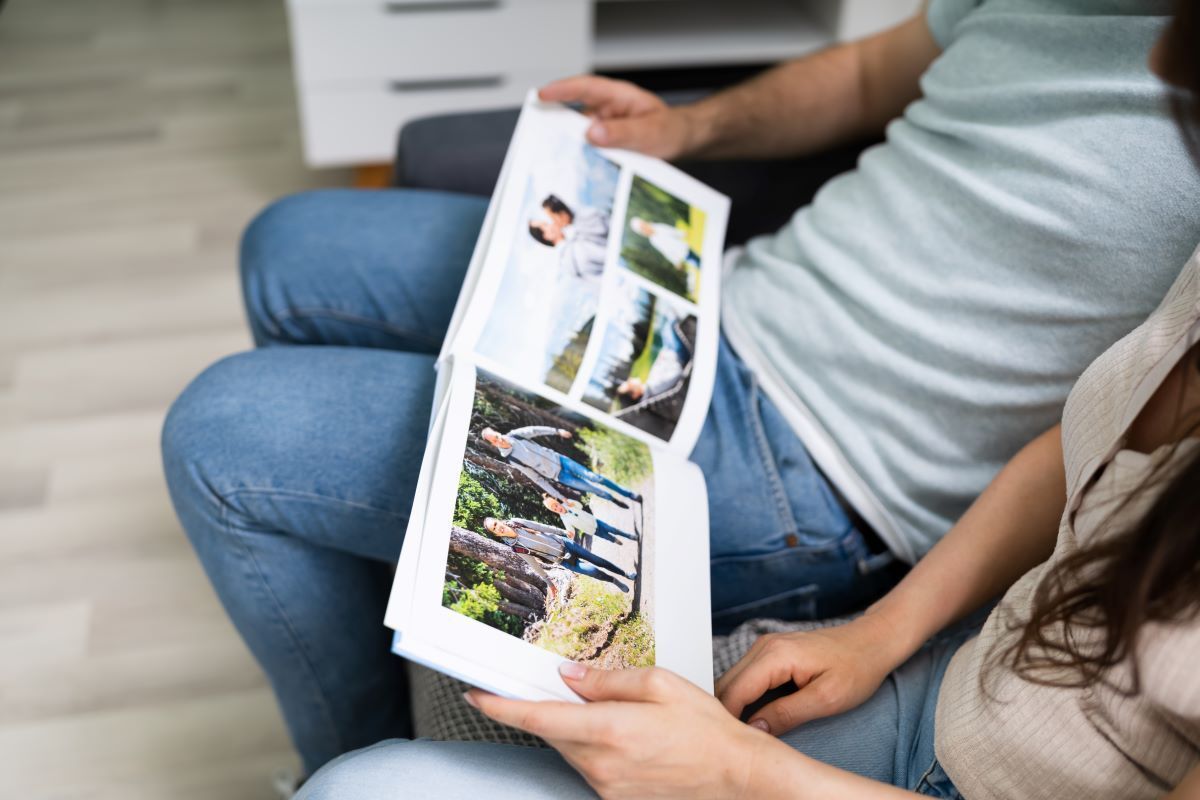 A man and a woman are sitting on a couch looking at a photo album.
