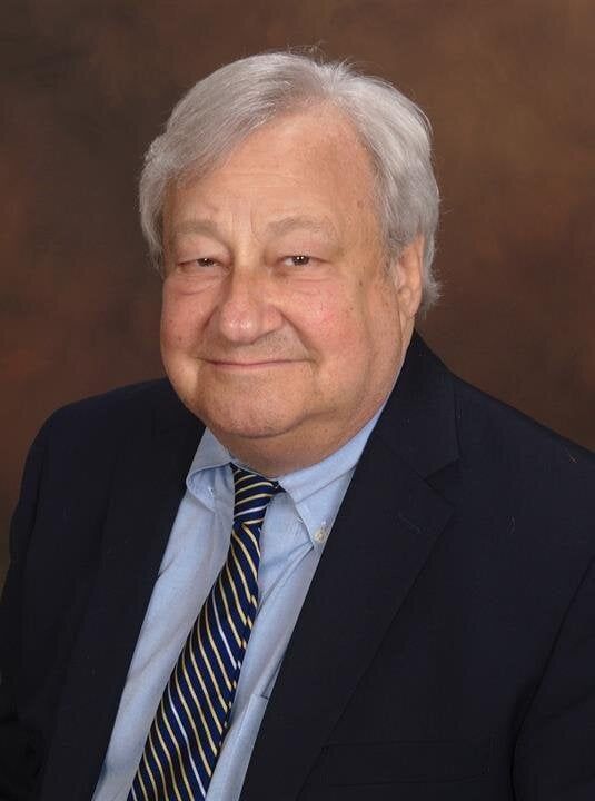A man in a suit and tie is smiling for the camera