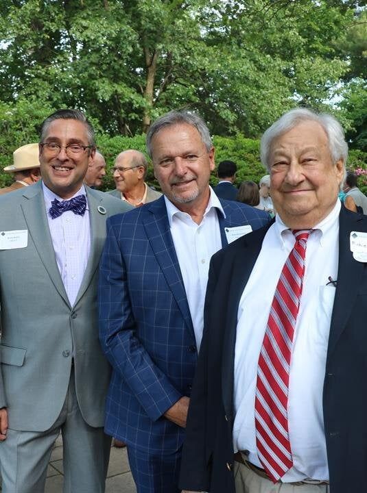 Three men in suits and ties are posing for a picture.