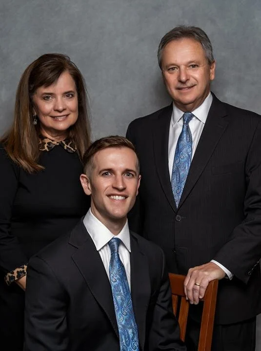 A man in a suit and tie is posing for a picture with his family