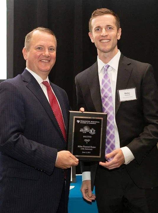 Two men in suits and ties are holding a plaque