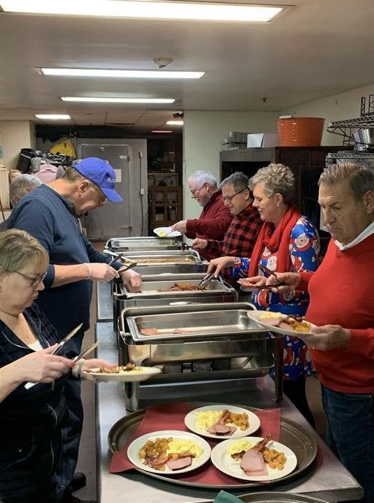 A group of people are standing at a buffet line eating food.