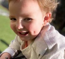 A close up of a baby with a slight smirk on his face.