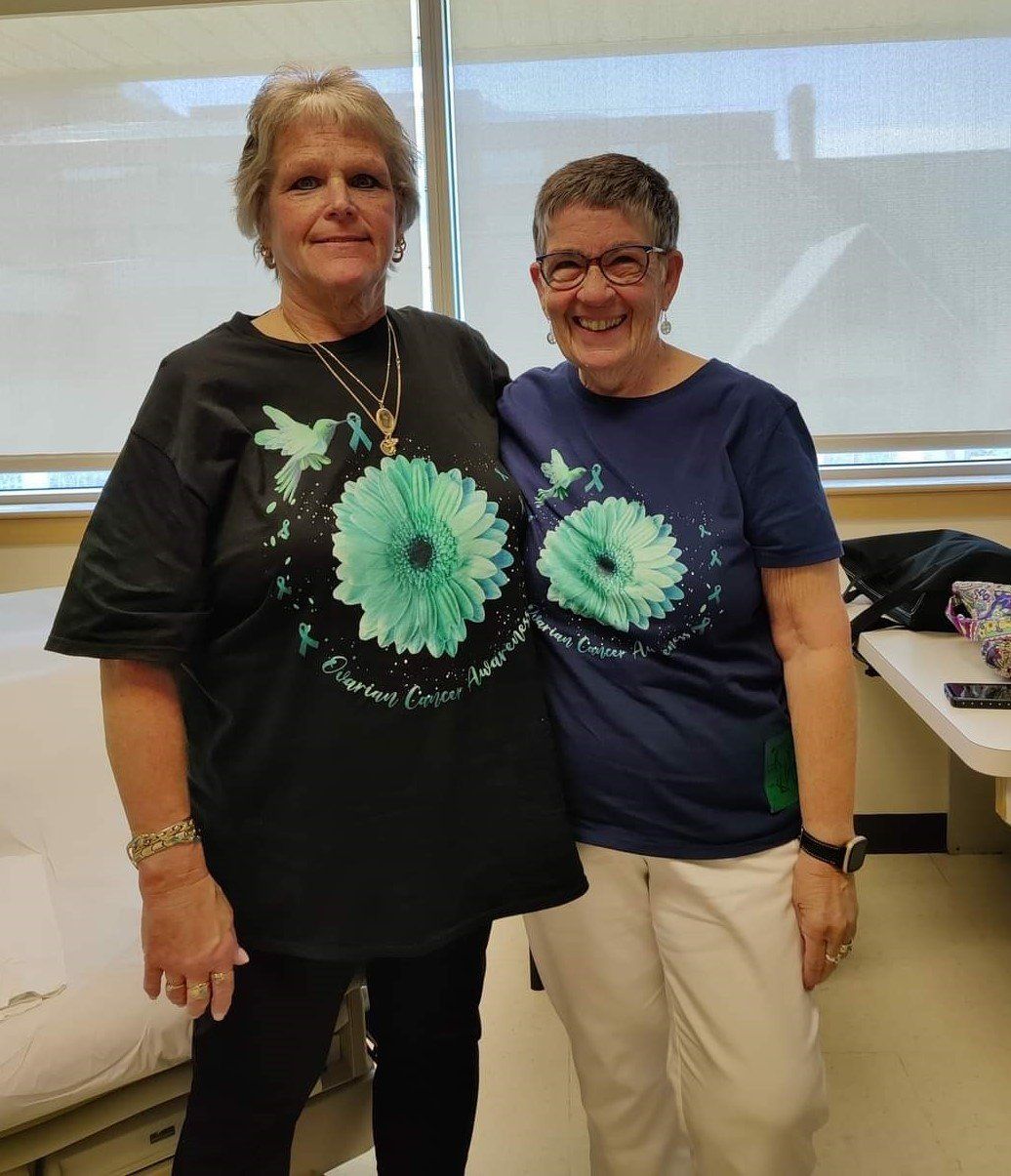 Two women standing next to each other wearing matching shirts