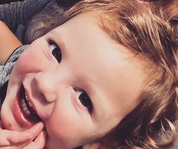 A close up of a little boy smiling with his mouth open