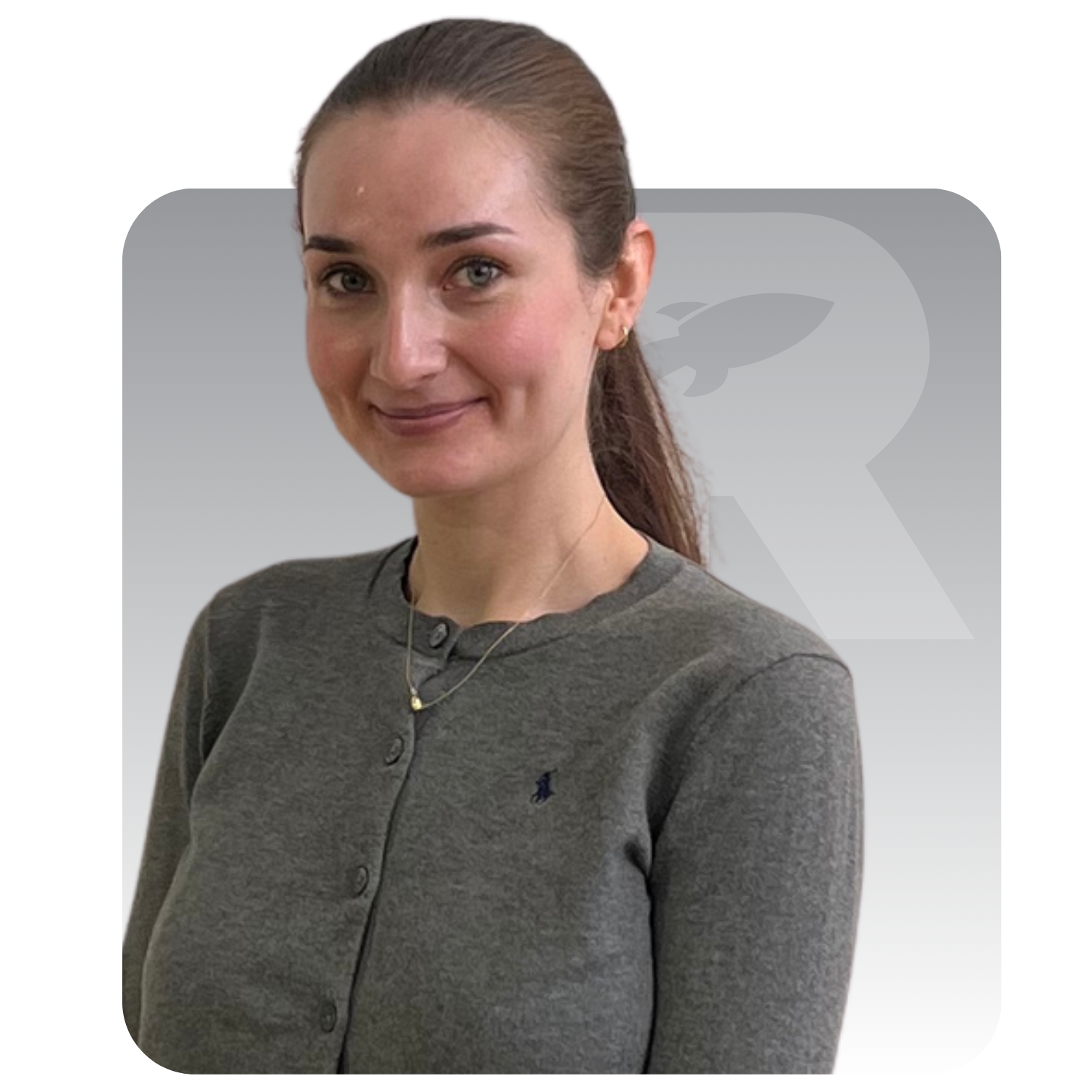 Woman with hair tied back, wearing a gray sweater, standing against a light gray background.