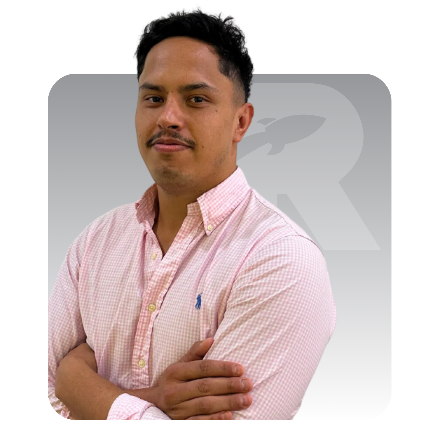 A man in a pink shirt is standing with his arms crossed.