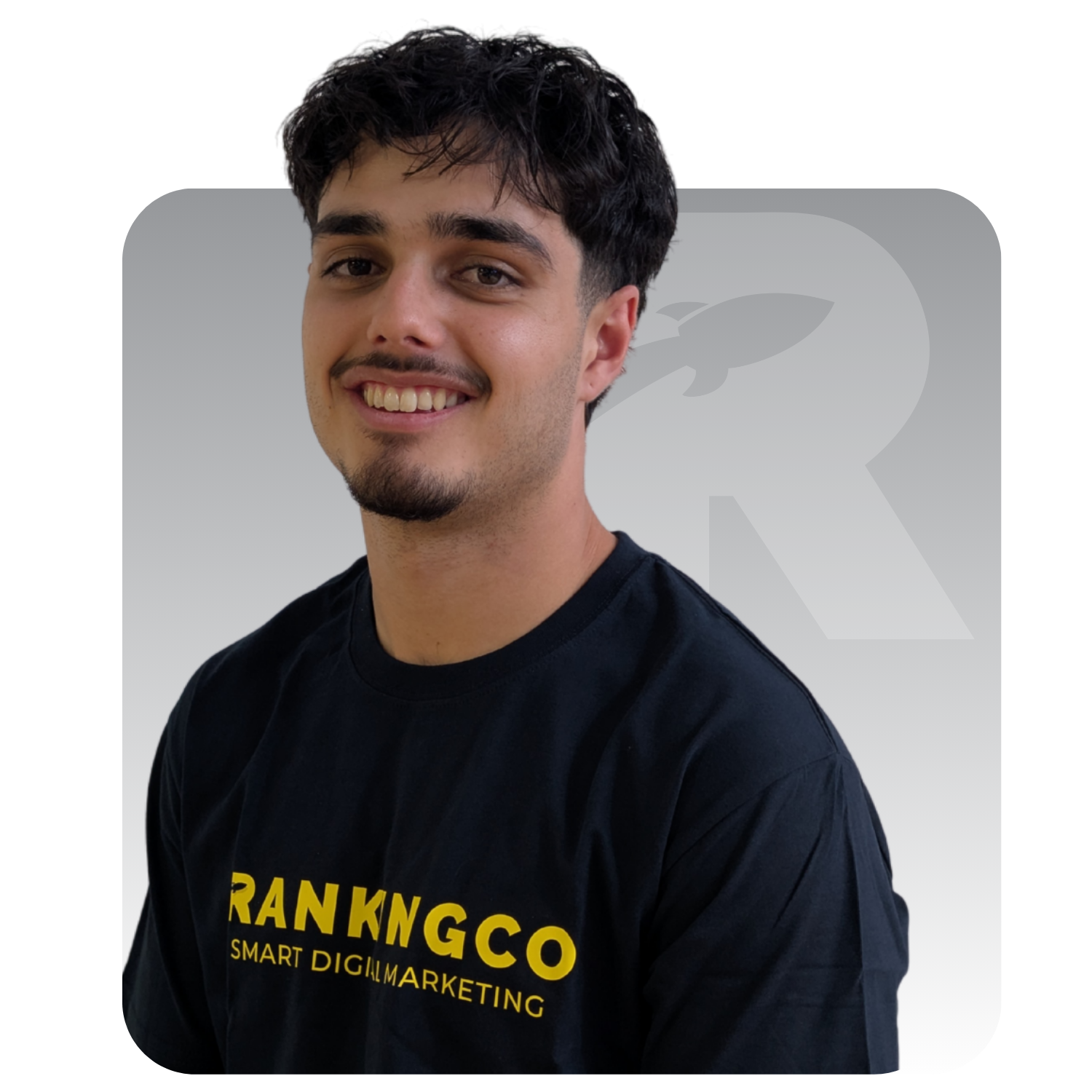 Smiling man in a black T-shirt with yellow logo, against a light gray background