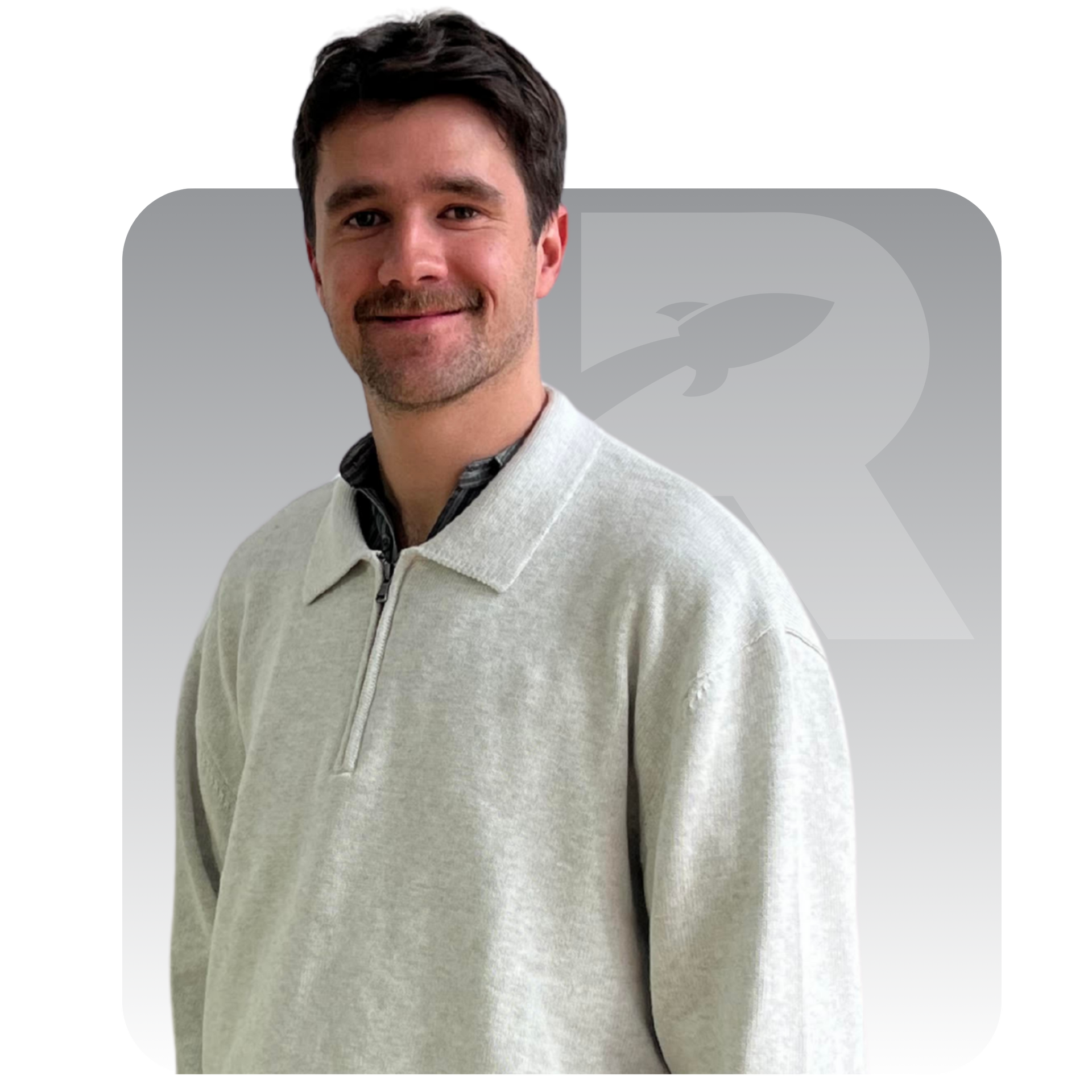 Portrait of a man in a grey sweater against a white background with a faint logo