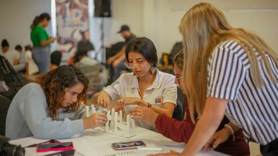 A group of young women are sitting around a table working on a project.