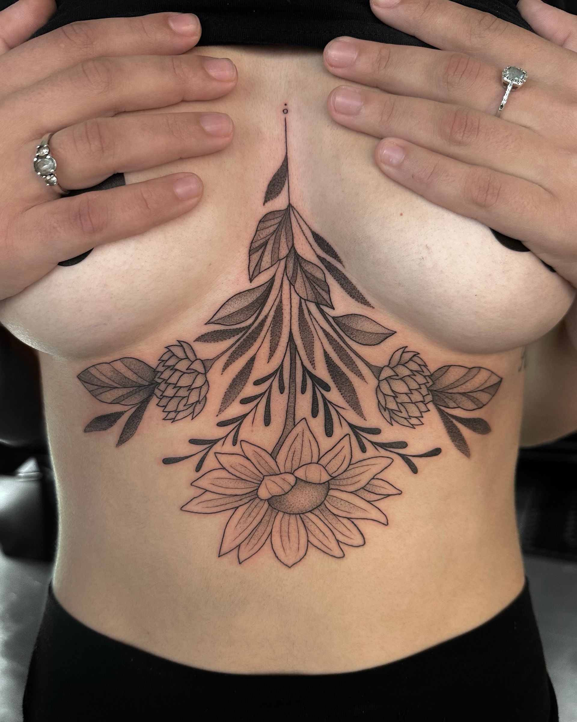 Floral tattoo design on a person's chest, featuring a sunflower and foliage.