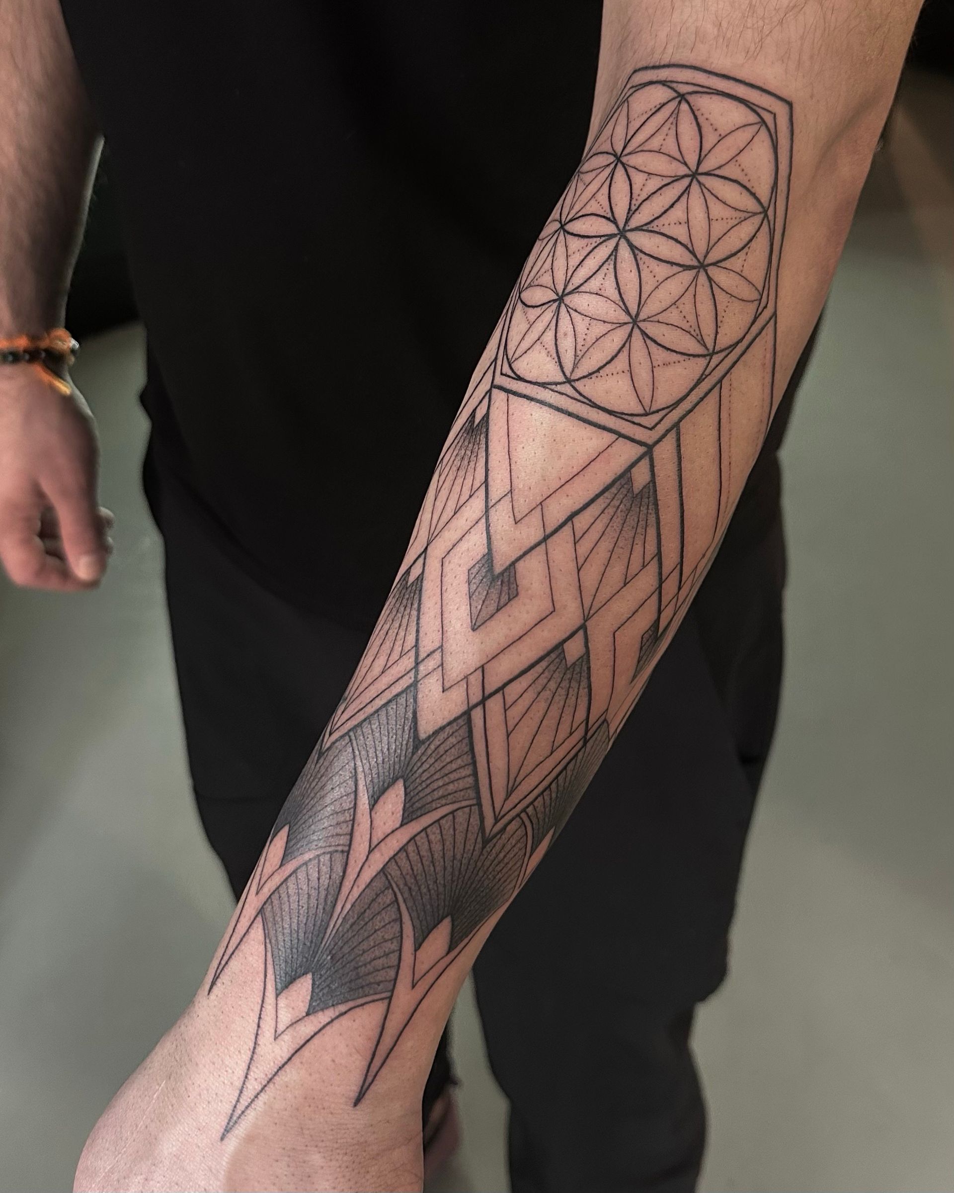 Geometric tattoo on forearm featuring overlapping shapes and the Flower of Life.