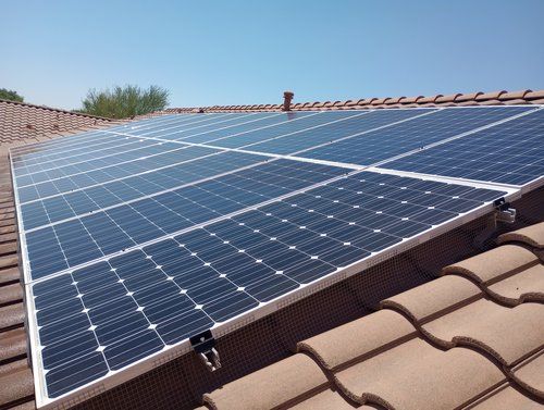 There are many solar panels on the roof of a house.