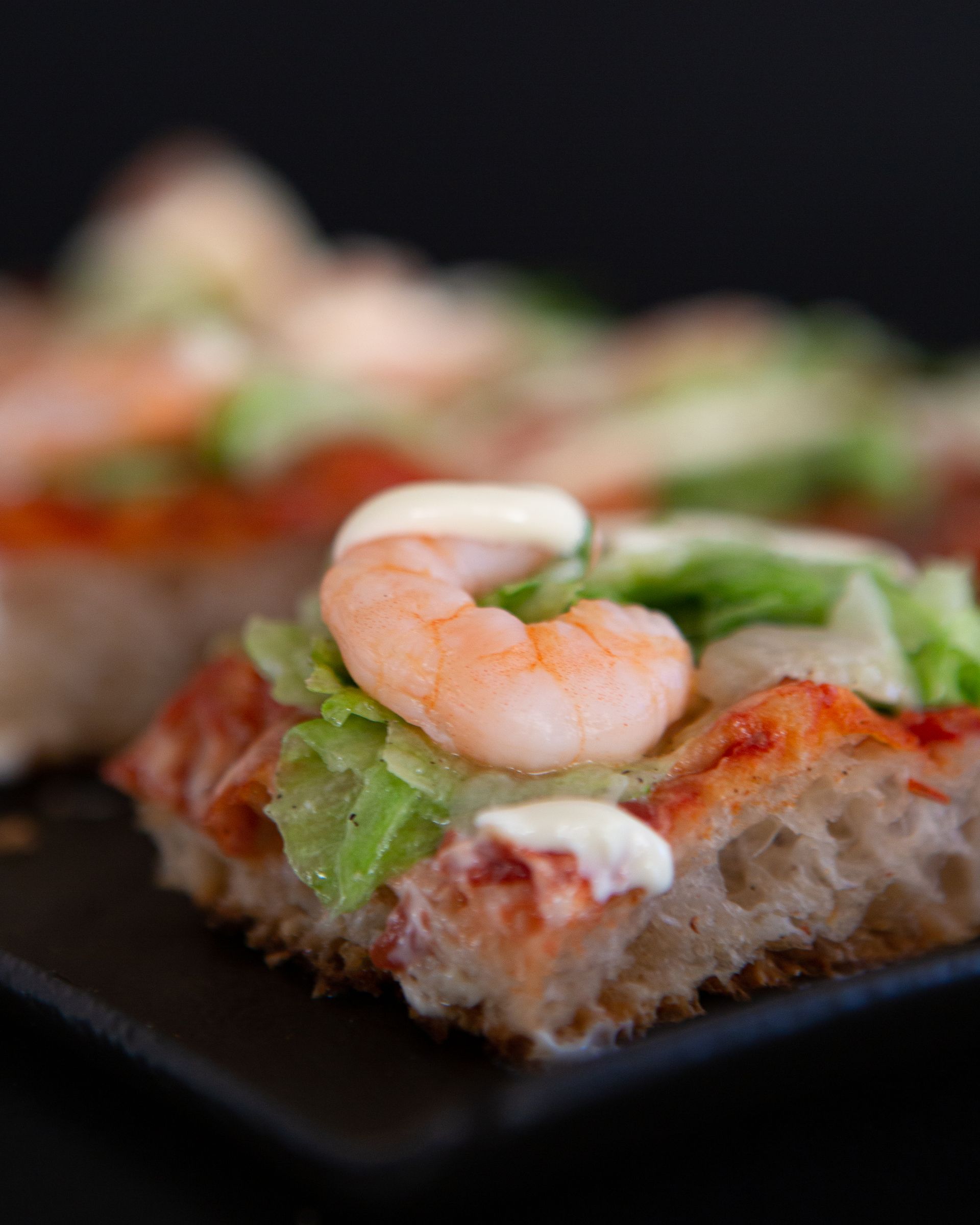 Crostini con gamberetti, lattuga e salsa su un piatto scuro
