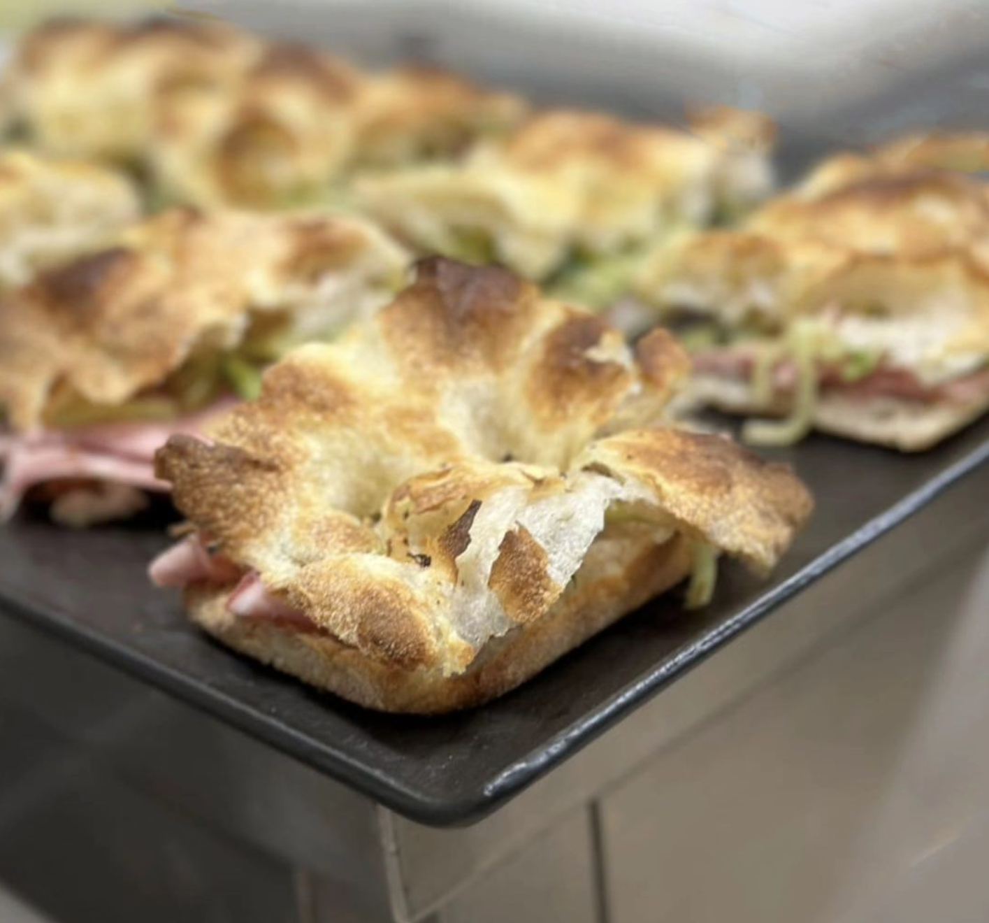 Vassoio di pasticcini dorati con prosciutto e lattuga su una teglia da forno