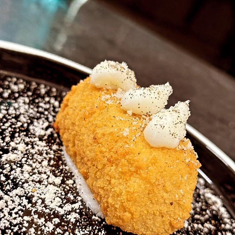 Dessert ricoperto di briciole d'arancia e guarnito con panna montata su un piatto con salsa al cioccolato fondente.