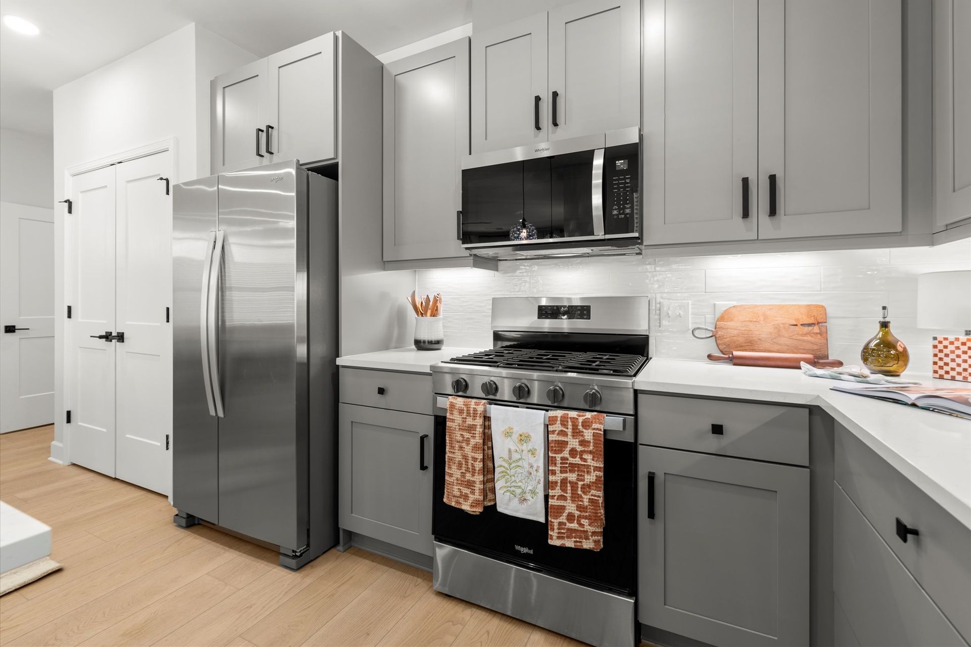 Gray kitchen with stainless steel appliances and white countertops.