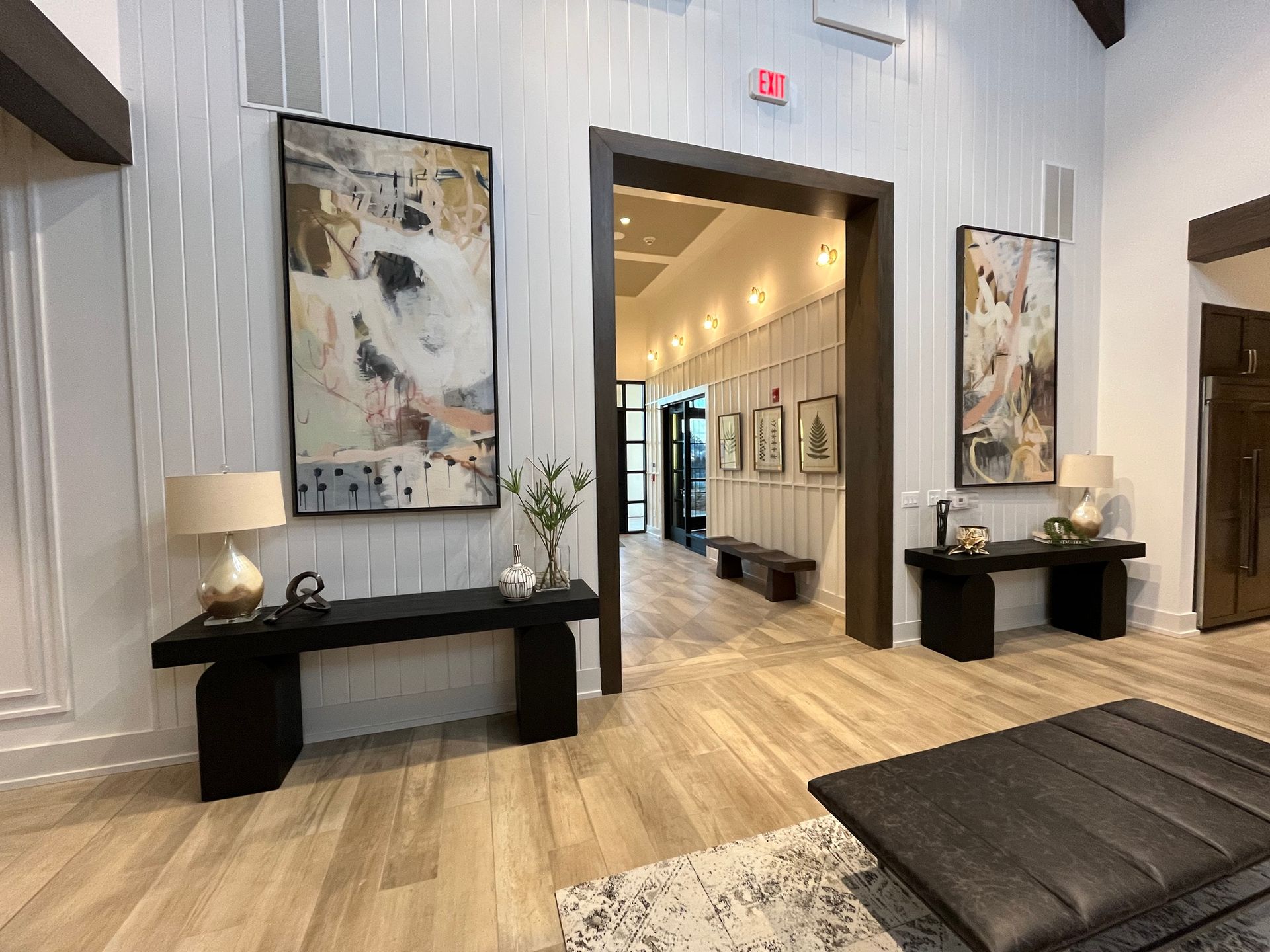 Lobby with wood floors, artwork, and benches. Features a hallway view with more artwork. Light and dark colors.