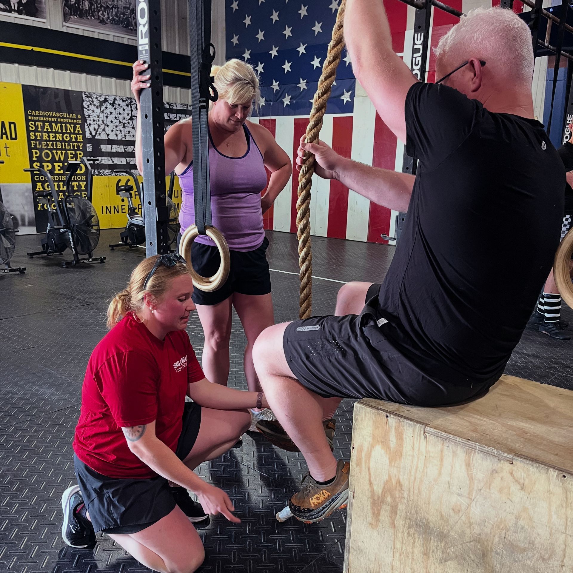 Person lifting a barbell on a gym floor in Springfield, OH while another person watches nearby.