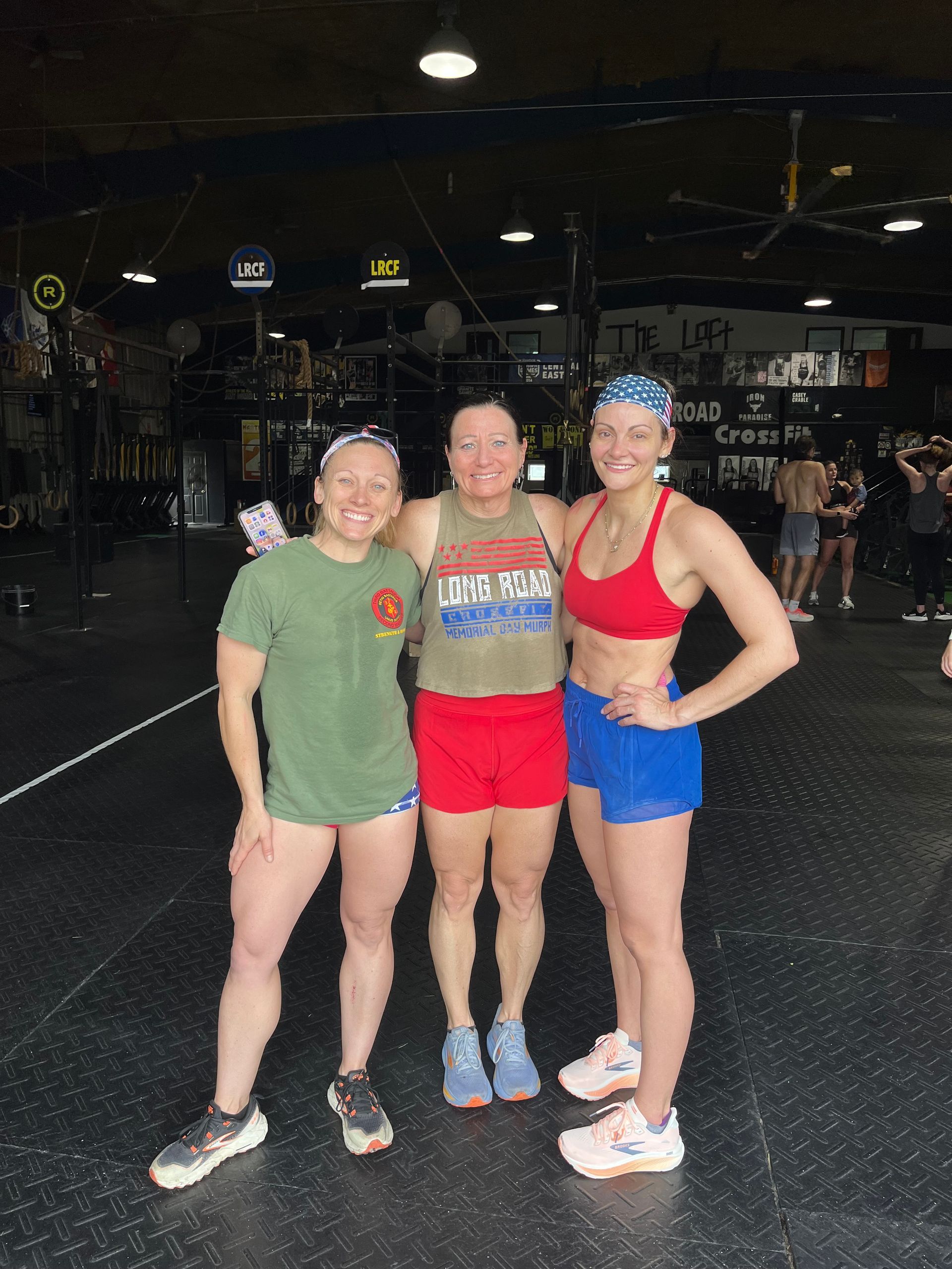 Three runners posing indoors, wearing colorful athletic outfits and smiling at the camera.