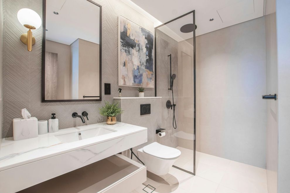 Modern white bathroom with floating sink, mirror, toilet, glass shower, and abstract wall art