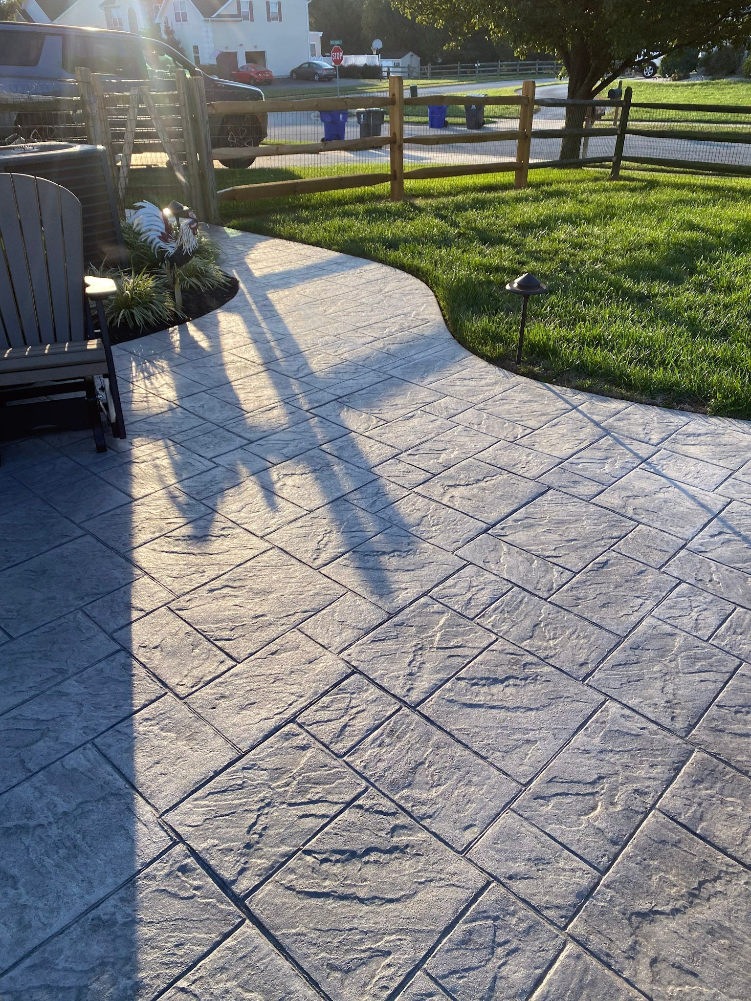 a  stamped concrete  patio with a chair and a fence in the background .