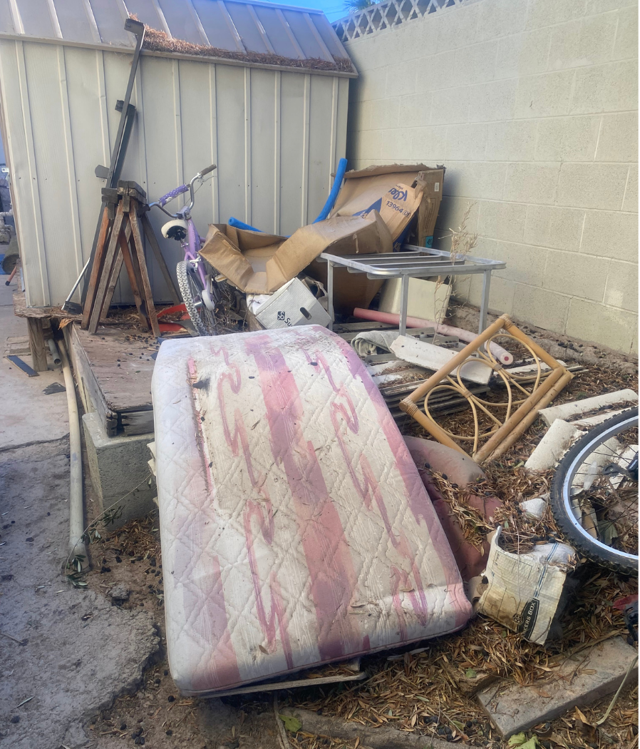 A pile of trash is sitting in front of a shed.