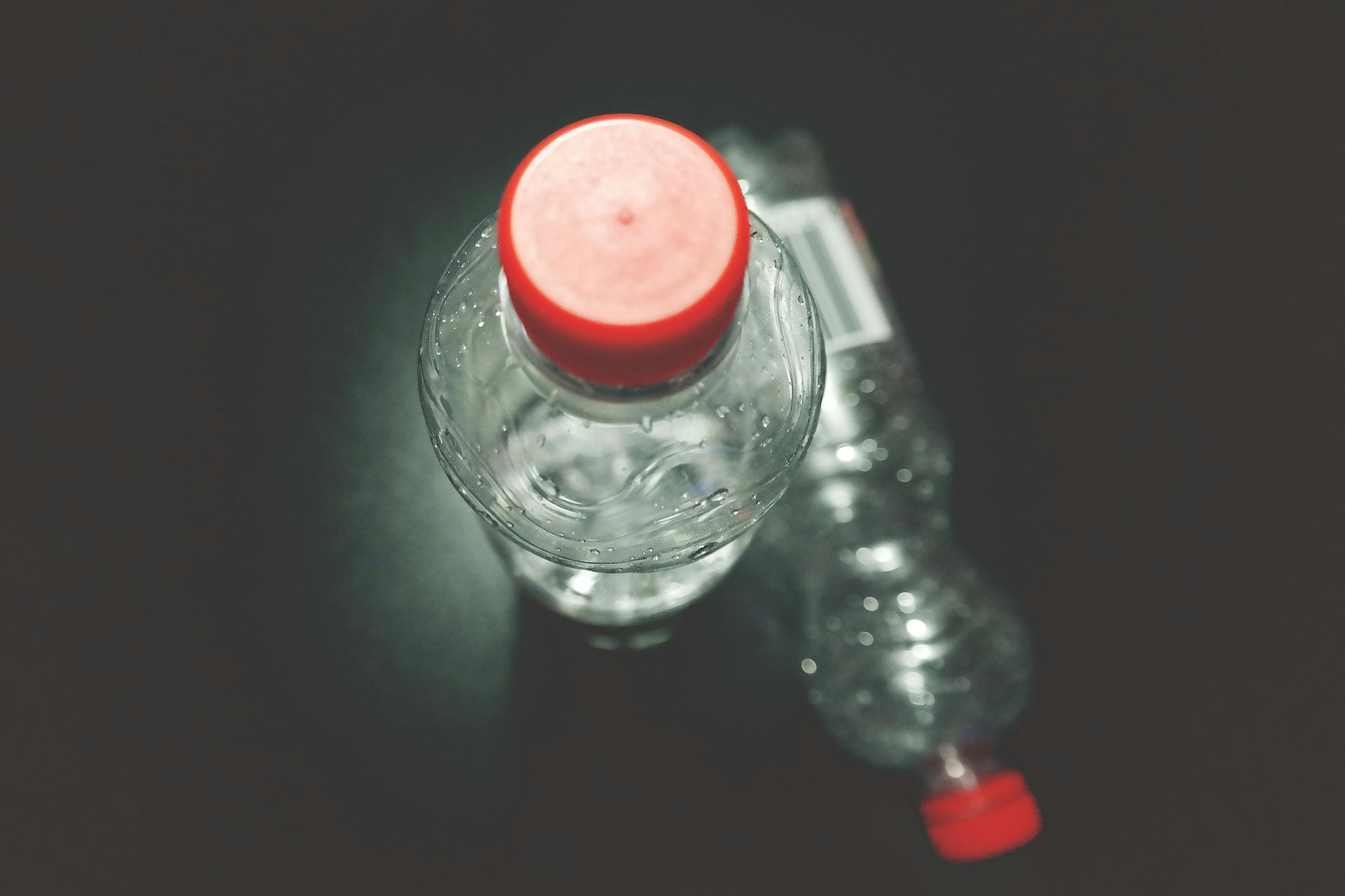 A bottle of water with a red cap is sitting on top of another bottle of water.