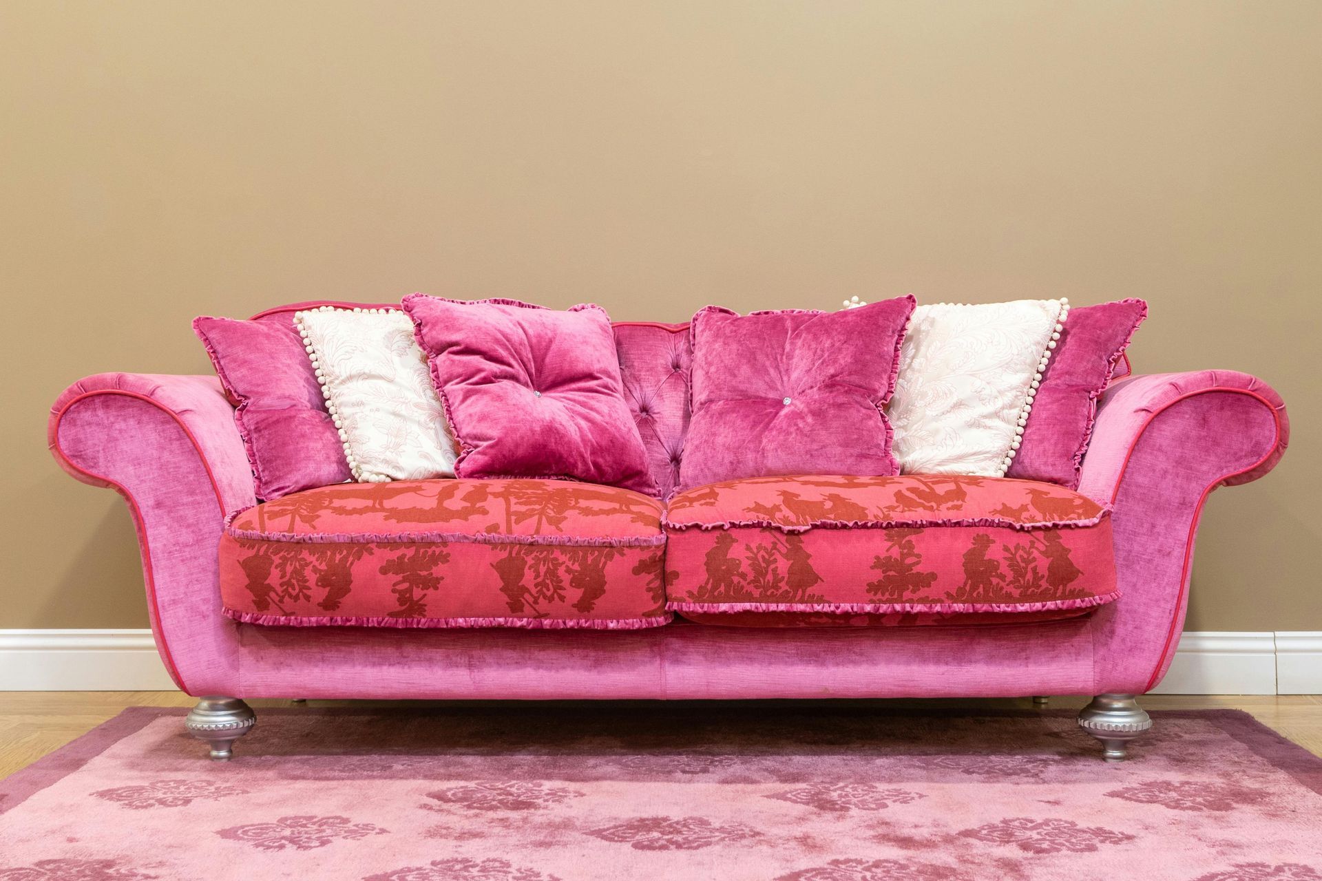 A pink couch is sitting on a pink rug in a living room.