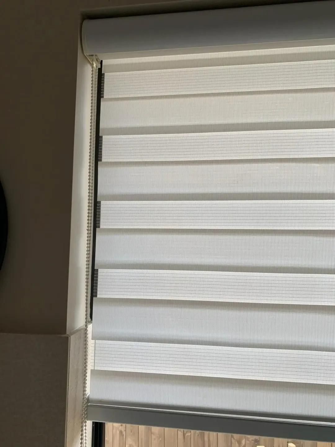 A White Blind is Hanging on a Window in a Room — Mi-ekka Designs in Mackay, QLD