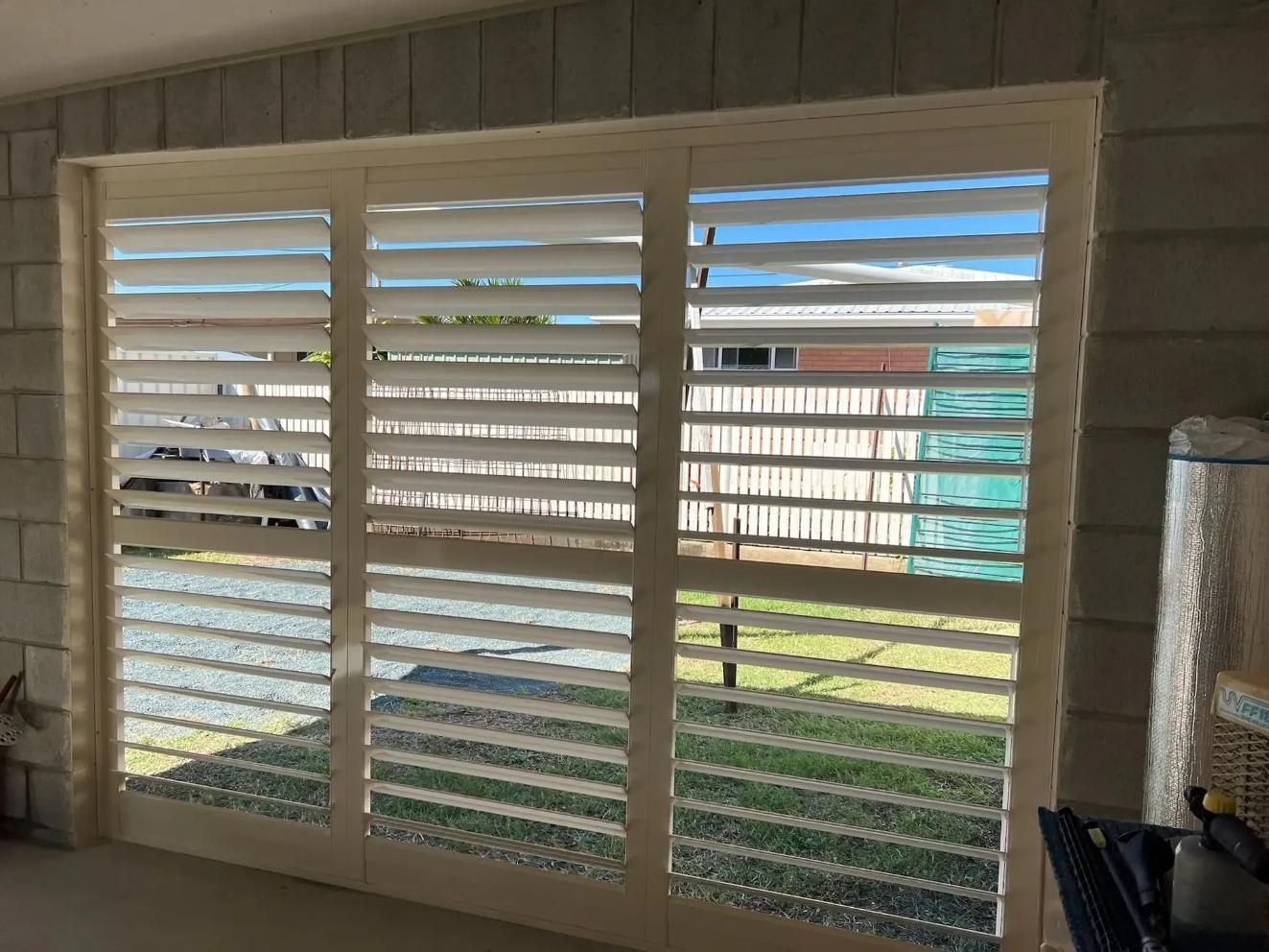 A Sliding Glass Door With White Shutters on It — Mi-ekka Designs in Hamilton Island, QLD