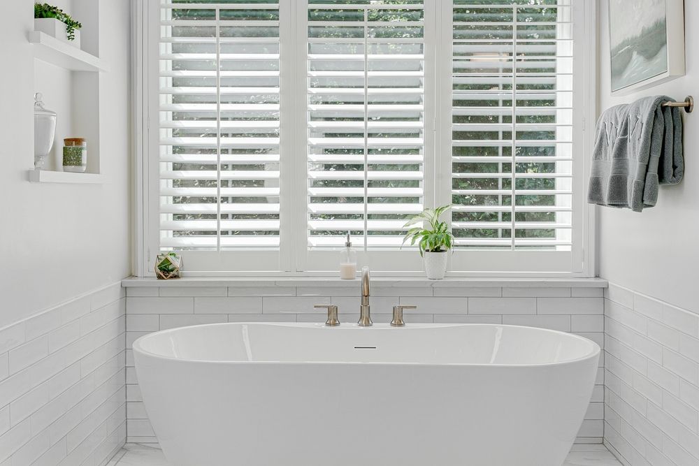 A Bathroom With a Bathtub and a Window With Shutters — Mi-ekka Designs in Cannonvale, QLD