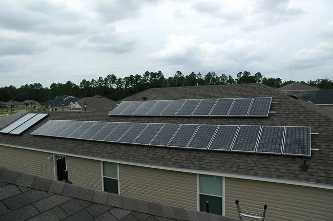 Rooftop solar panels on a suburban house under a cloudy sky