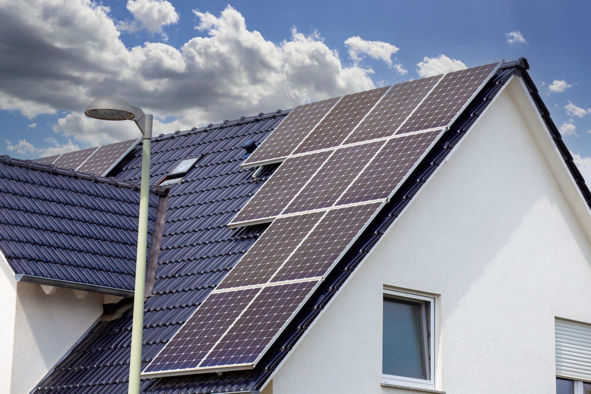 House roof with solar panels under a cloudy sky
