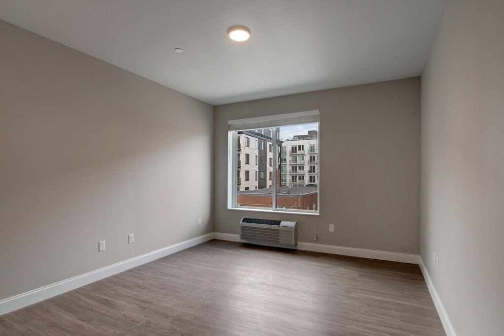 An empty room with a window and a heater at Daymark Uptown Apartments.