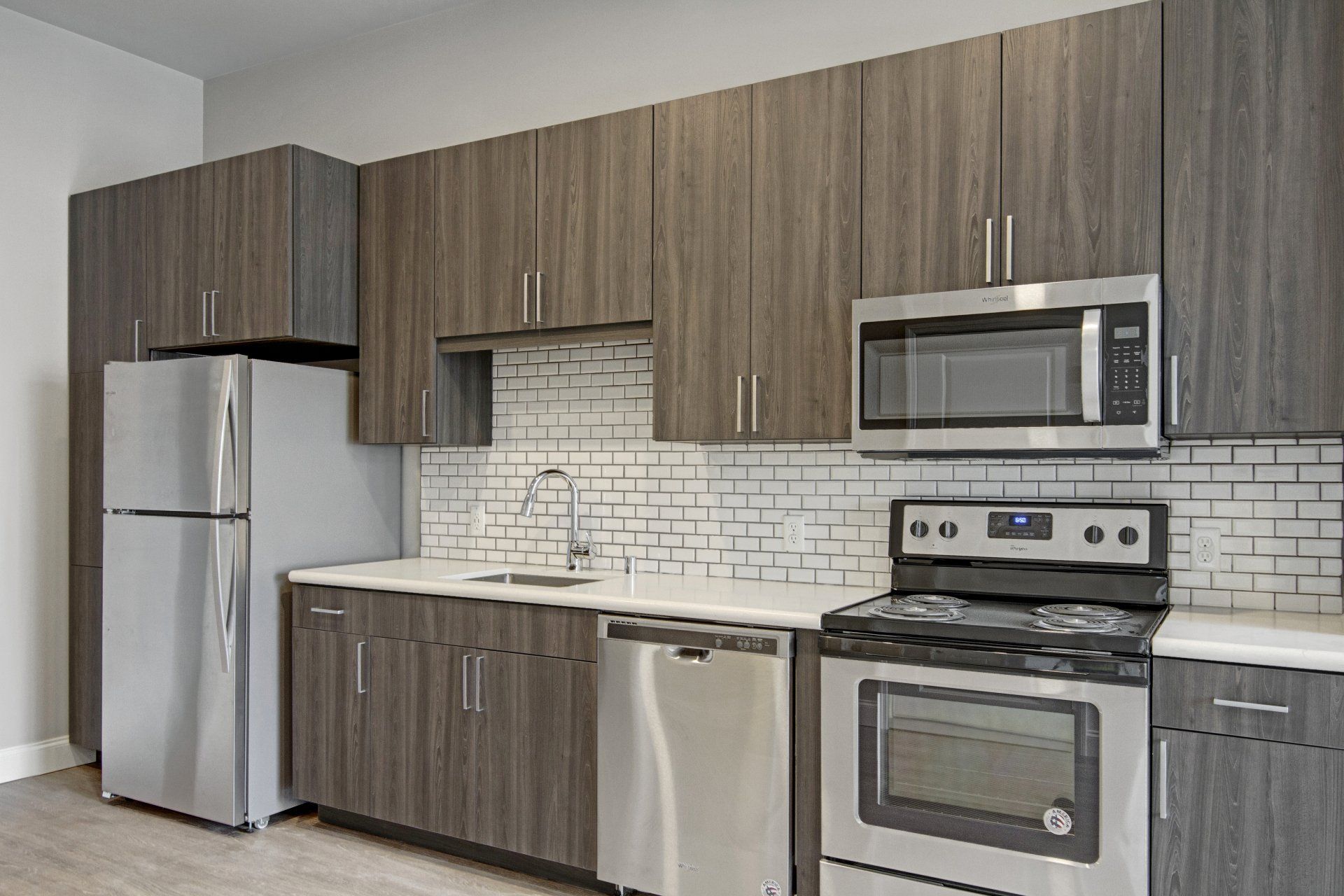 A kitchen with stainless steel appliances and wooden cabinets at Daymark Uptown Apartments.