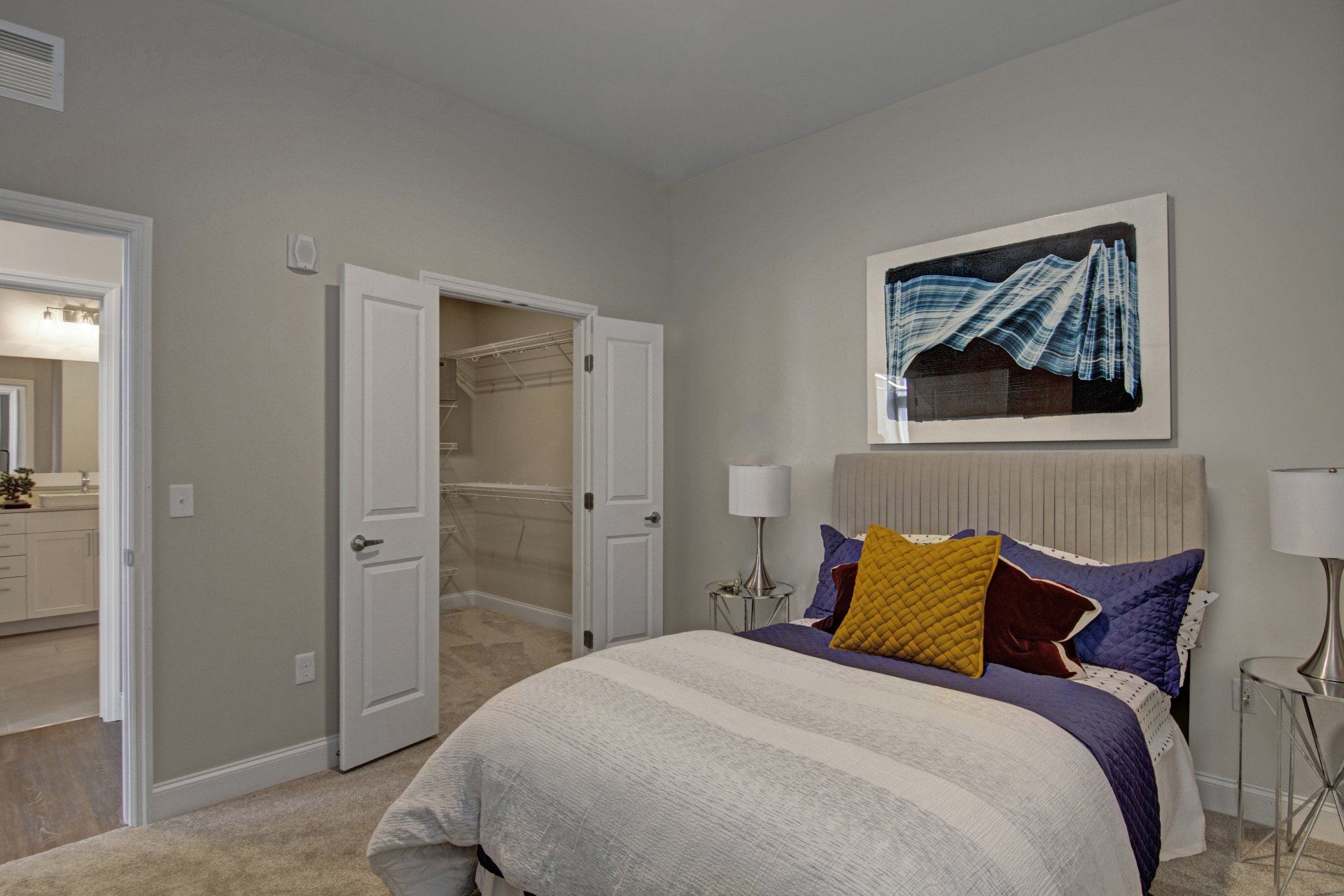 A bedroom with a large bed and a walk in closet at Daymark Uptown Apartments.
