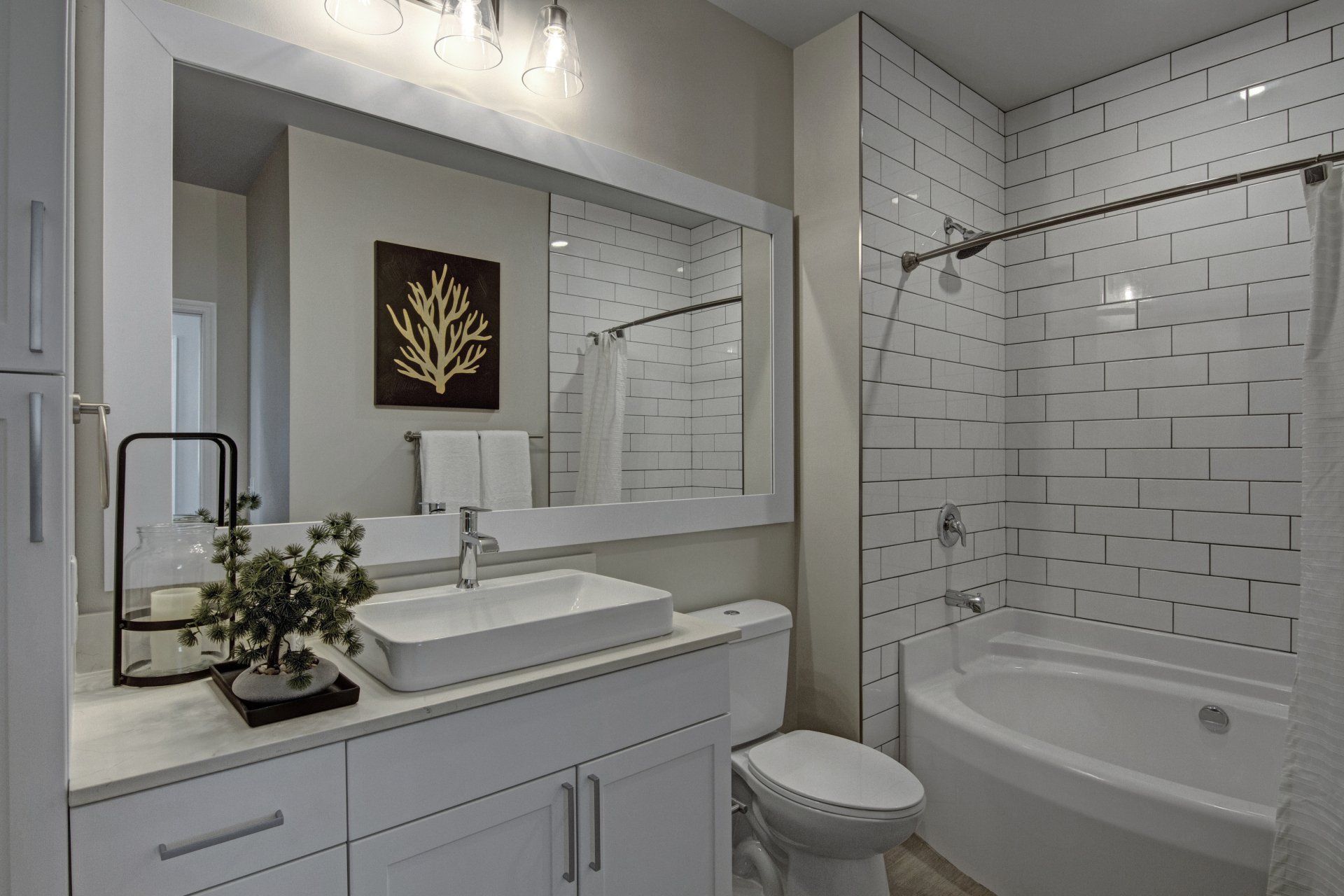 A bathroom with a sink, toilet, tub, and mirror at Daymark Uptown Apartments.