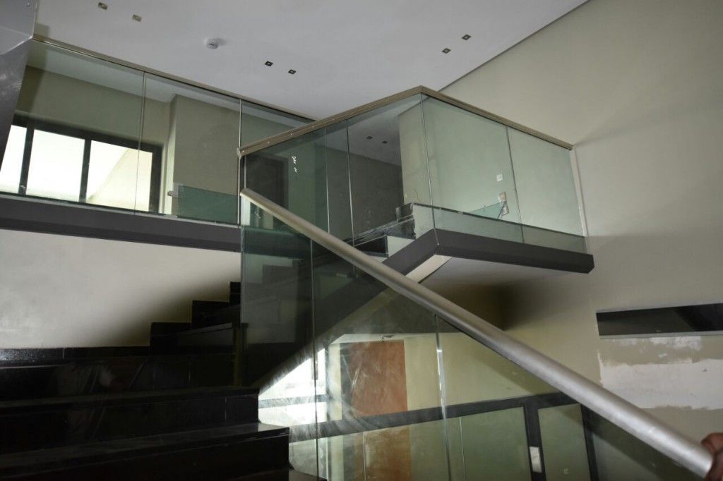 Scala interna con ringhiere in vetro e gradini scuri nella hall di un edificio moderno.
