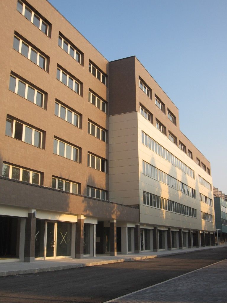 Esterno di un moderno edificio residenziale con file di finestre e una strada antistante al tramonto.