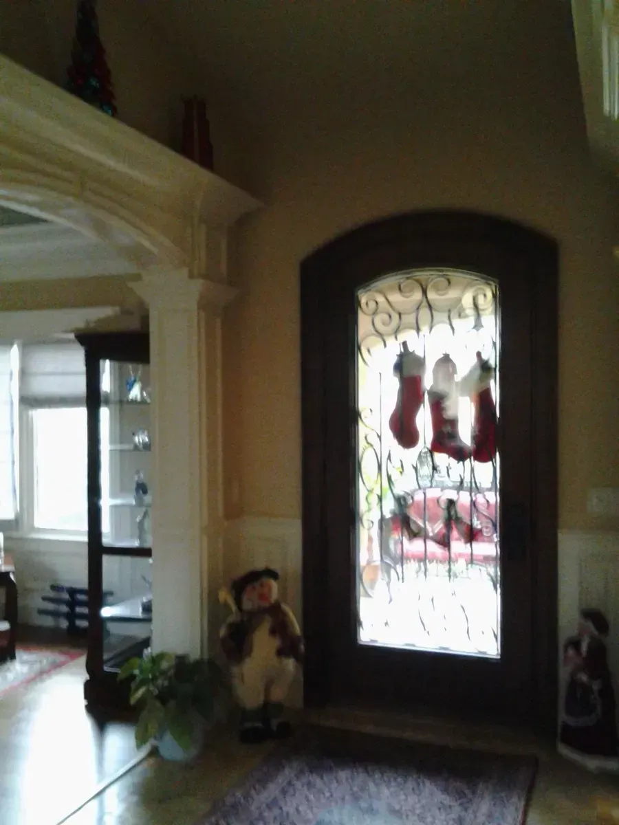Front entryway with a decorative glass door, a small figurine by the wall, and a bright hallway beyond.