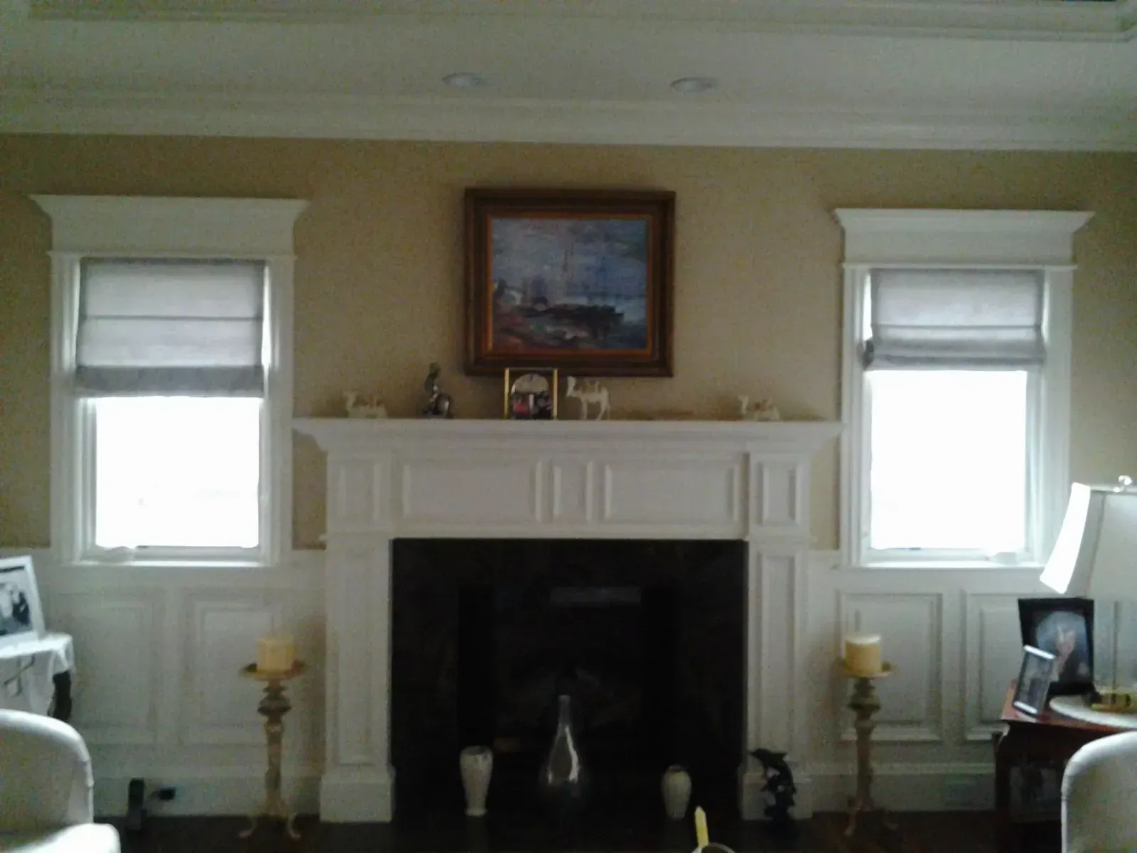 Living room with a white fireplace, framed painting, and windows on either side