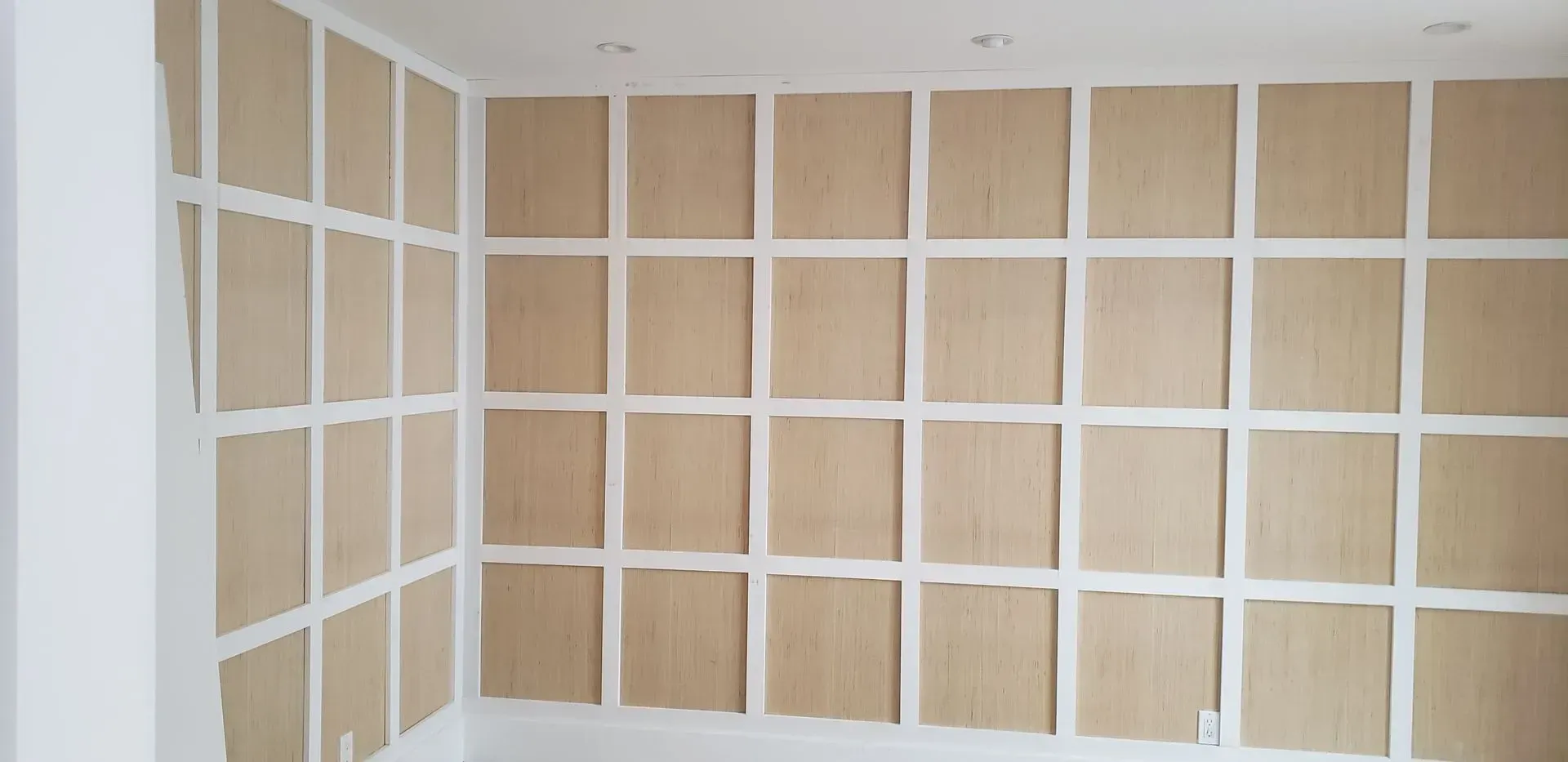 Interior wall covered with unfinished white grid panels and light wood backing boards