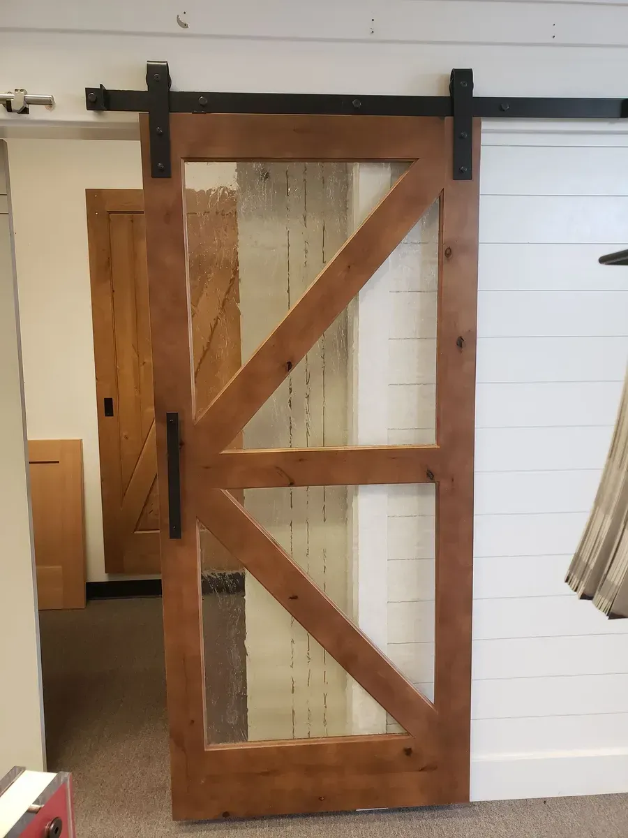 Wooden sliding barn door with diagonal bracing, hanging on black hardware in an indoor room