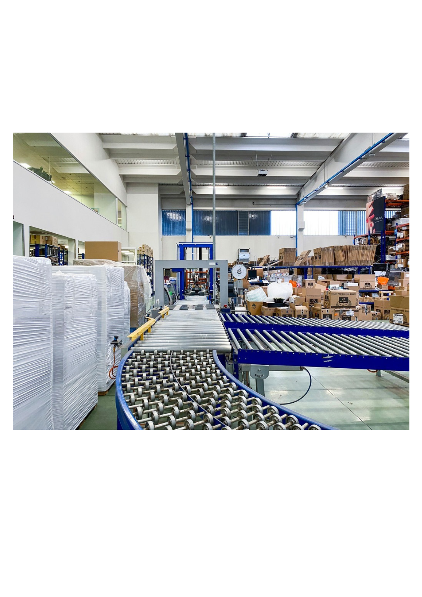 Magazzino industriale caratterizzato da un sistema di nastri trasportatori a rulli metallici.
