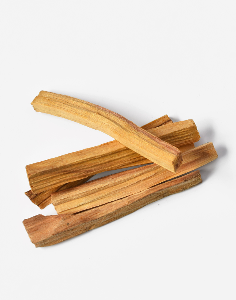 Un piccolo mucchio di bastoncini di legno di palo santo di colore marrone chiaro, adagiati su uno sfondo bianco uniforme.