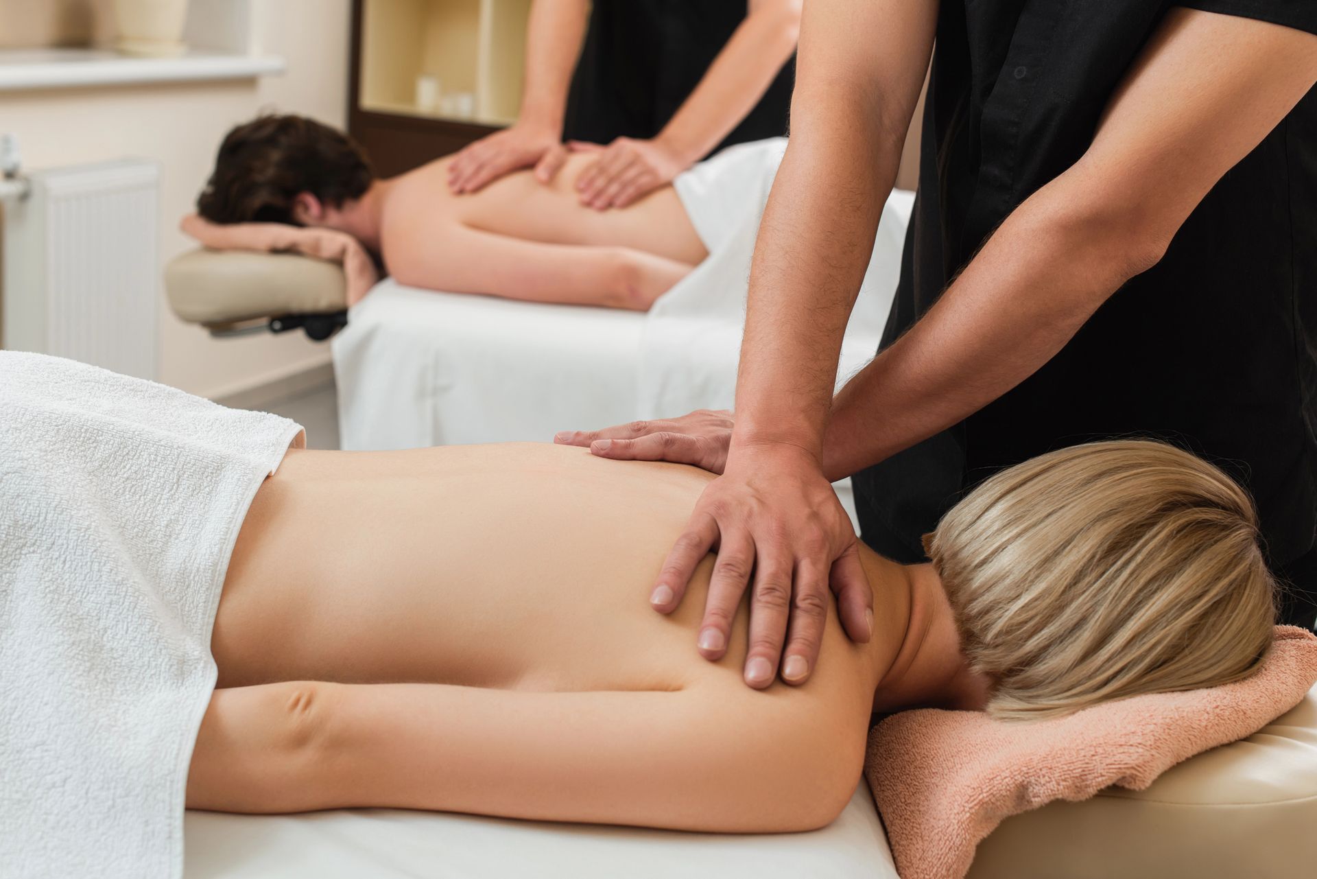 Sala spa con proiezione di scene di giardini giapponesi. Lettini per massaggi, pavimento in legno, luci soffuse.